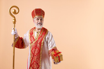 Fototapeta premium Saint Nicholas with gift on beige background. Space for text