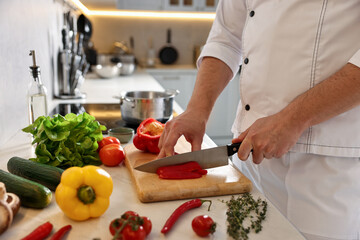 Professional chef cutting bell pepper at counter in kitchen, closeup