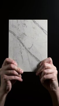 Luxury quartz stone texture pattern with trendy curly veins. Marble slab in hand on black background in Slow motion