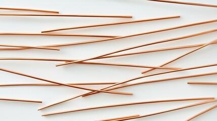 Copper metal rods arranged randomly on a white surface showcasing industrial materials in a simplistic layout