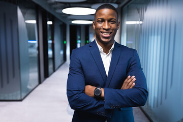 African American man standing confidently in office hallway, wearing navy suit and smartwatch