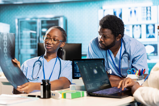 Team of trainee nurses analyzing patient health records during a meeting, utilizing x ray and mri scans with expert physician for a training session. Assistants work with medic.