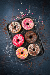 Traditional festive glazed doughnuts with icing sugar and chocolate decorated with colorful...