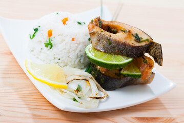 Image of deliciously baked trout steaks, served with lemon and rice at plate