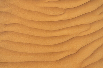 Background of desert sand with curved deep rippled dunes. Top view close-up. Space for text. Sand...
