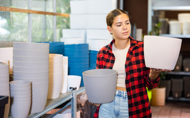Portrait of a young European woman choosing flower pots for indoor plants at the gardening market