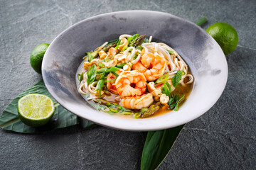 Authentical Asia style ramen noodle soup with prawns and cashew nuts served as top view in a design bowl