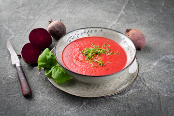 Healthy vegetarian creamy beetroot soup pureed blend served with cress and basil as close-up in a...