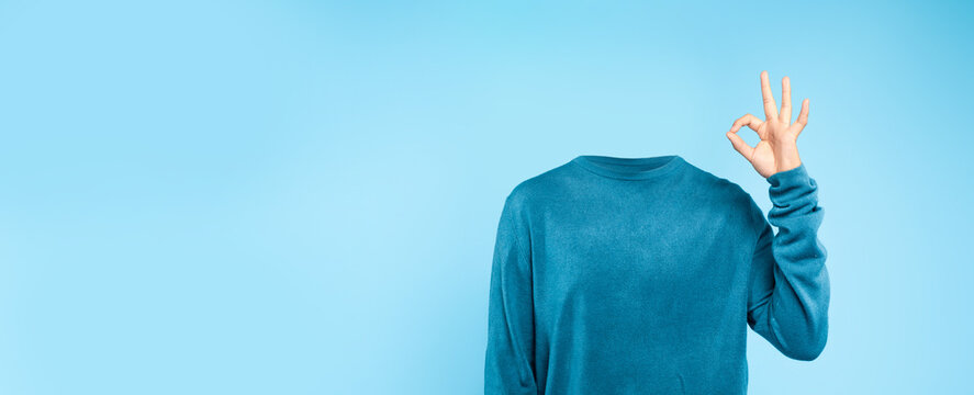 A headless individual dressed in a blue sweater makes a gesture of approval against a plain blue backdrop. This unique representation emphasizes a minimalist and surreal lifestyle concept.