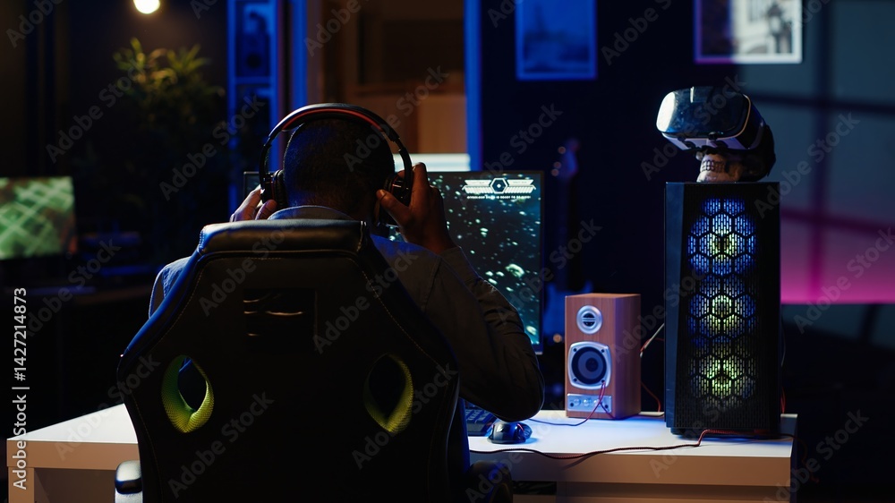 Poster man playing sf space videogame on pc screen in neon illuminated apartment living room. gamer enjoyin
