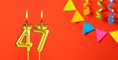 Number 47 candle - Birthday celebration on an orange background with pennants