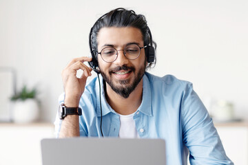 Distance Learning. Positive Young Arab Guy In Headset Watching Webinar On Laptop At Home, Having...