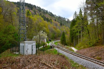 Railroad leading past a forest covered hill in springtime in Gorenjska, Slovenia