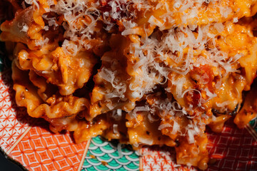 close up of tomato sauce, parmesan cheese on mafalde pasta