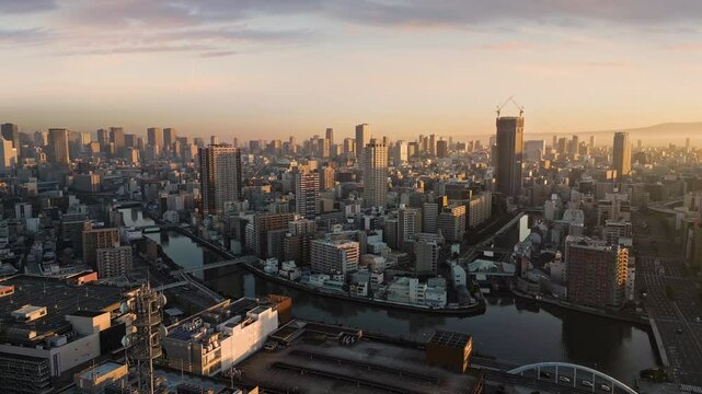 osaka city skyline business district aerial shot drone pan over downtown at sunrise,high rise modern office buildings,view of nishi ku ward and town centre,kizu and dotombori river
