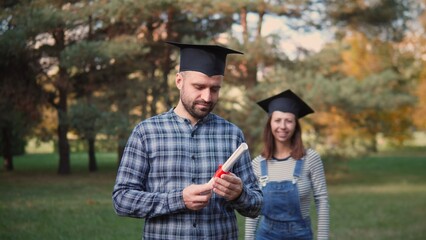 Two proud graduates celebrate their achievements outdoors, showcasing joy and accomplishment with...