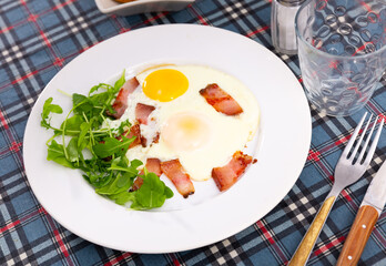 Delicious hearty breakfast with scrambled eggs, bacon and arugula