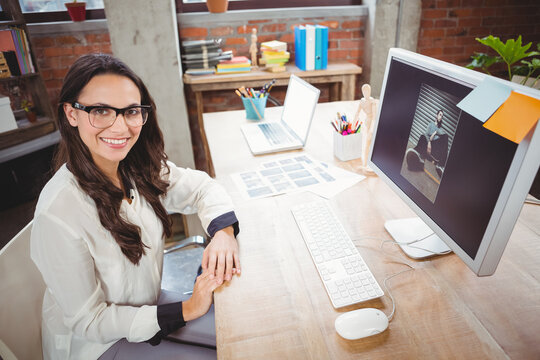 Young adult woman working on color swatches at office desk with monitor and plant, copy space - Powered by Adobe