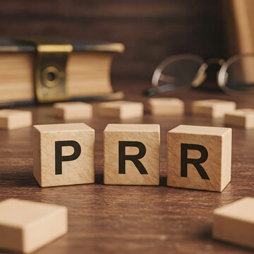 Three wooden blocks displaying the letters PRR on a wooden surface