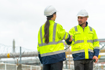 Petrochemical industry engineer teamwork shaking hands after success working plan at petroleum oil refinery plant. Industrial engineering technician working manufacturing energy power gas system.
