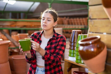 Portrait of woman choosing pots for flowers and trees in gardening market