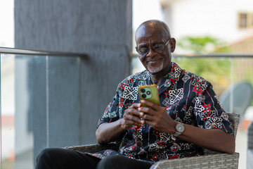 Elderly African man uses his smartphone for internet banking sending money.