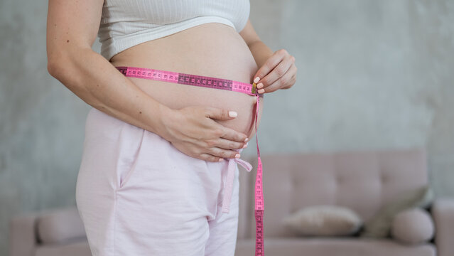 Pregnant woman measuring her belly. 