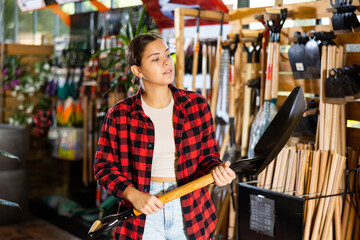 Young woman gardener standing in a warehouse in the greenhouse of a flower shop selects working...