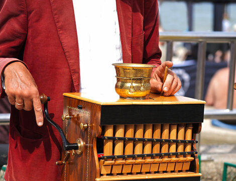 The organ-grinder plays on vintage beautiful wooden barrel organ closeup.