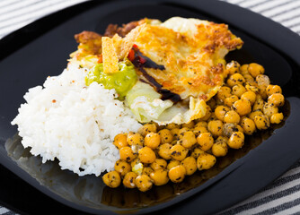 Breaded cabbage leaves with tomato and avocado sauces, white rice and spicy garbanzos on black dish
