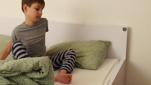 Teenager boy makes bed at the morning