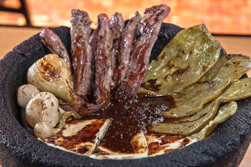 Mexican food, Aztec molcajete with skirt steak, drunken sauce, nopales and fresh cheese, molcajete sauce, food