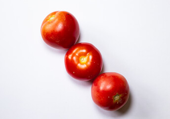 Three vibrant red tomatoes, arranged in a neat row against a plain white background.