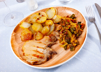 Grilled pork meat with roasted potatoes and braised cabbage served on table.