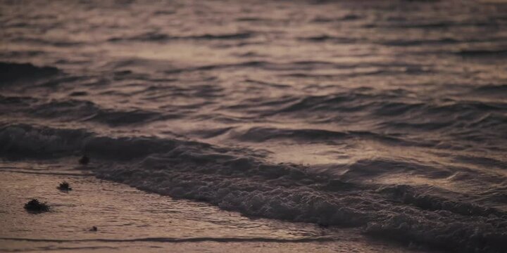 close up a contraluz de las olas a la orilla de la playa reflejando la luz del amanecer, textura de las olas en la arena al amanecer