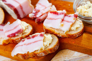 Delicious sandwiches with salted bacon and horseradish on a wooden surface. Close-up image..