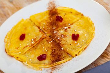 Warm crepes with cocoa, sugar powder and confiture for breakfast