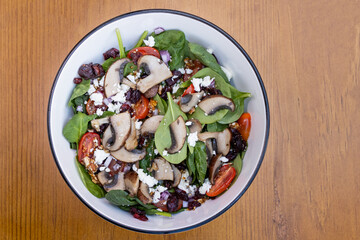 Gourmet vegetarian salad with mushrooms and leafy greens presented in a rustic bowl on a wooden background