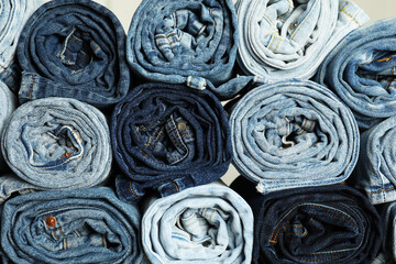 Different stylish rolled jeans as background, top view