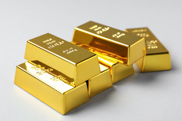 Shiny gold bars on light grey background, closeup