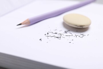 Eraser, pencil and scraps on notebook, closeup