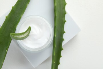 Moisturizing cream with extract of aloe vera and cut leaves on white background, flat lay