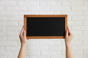 Woman holding blank small blackboard indoors, closeup