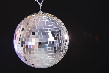 One shiny disco ball on dark background, space for text
