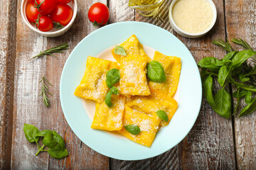 Delicious ravioli with cheese and basil served on wooden table, flat lay