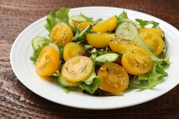 Fresh salad with yellow tomatoes on wooden table, closeup