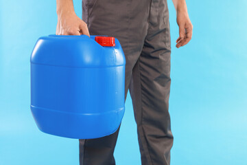 Man holding plastic canister on light blue background, closeup