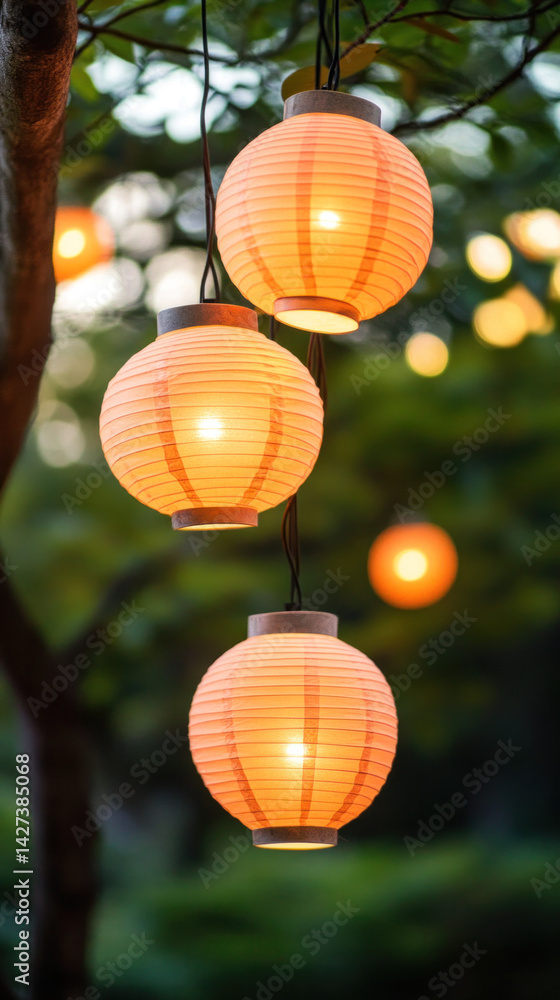 Poster a group of four orange lanterns hanging from a tree. the lanterns are lit and create a warm, invitin