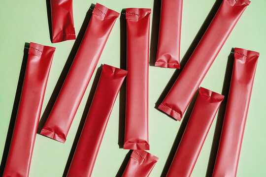 Red Stick Pack Sachet Packaging on Light Green Background. Product Presentation Mock Up.
