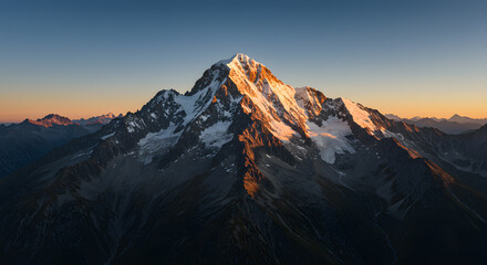 Obraz premium Majestic Mountain Illuminated by Sunset Light Against a Clear Sky